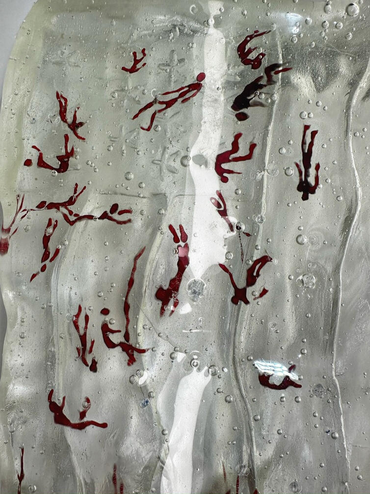 A cast glass sculpture of a tattered US flag with silhouettes of falling bodies cast into the glass itself.